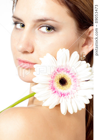 Portrait of beautiful woman with bright make up holding pink daisy in hands Portrait of beautiful woman with bright make up holding pink daisy in hands 89053473