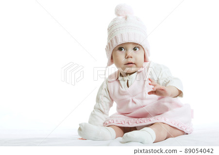 Little baby in knit winter clothing closing face with knitted beanie on the bed in the blue bedroom, New family and baby protection concept Little baby in knit winter clothing closing face with knitted beanie on the bed in the blue bedroom, New family and baby protection concept 89054042