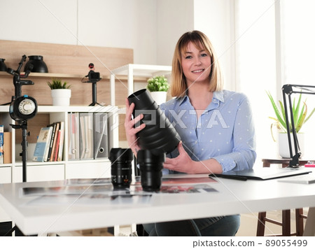 Female photographer working at office studio and holding a snoot reflector 89055499