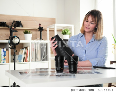 Female photographer working at office studio and holding a snoot reflector 89055503