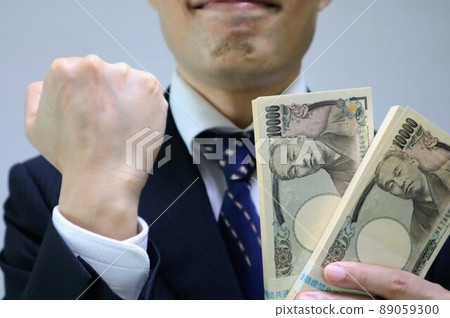 A businessman holding a wad of bills and making a guts pose A businessman holding a wad of bills and making a guts pose 89059300