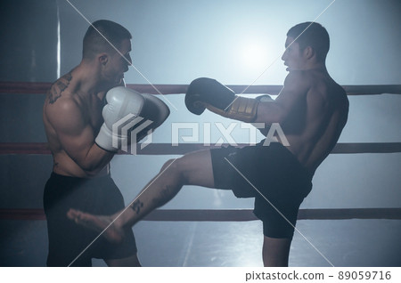 Two shirtless muscular man fighting Kick boxing combat in boxing ring. 89059716