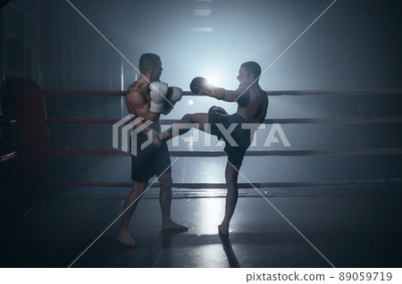 Two shirtless muscular man fighting Kick boxing combat in boxing ring. 89059719