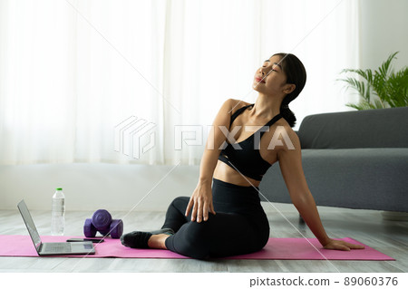 Fit sporty young asian woman online workout exercise at home. Active healthy girl enjoy sport pilates yoga fitness training on laptop computer stretching on yoga mat watching video class 89060376