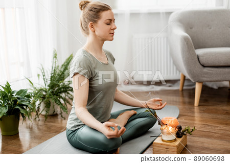 Beautiful happy girl with closed eyes practicing yoga in lotus position in bedroom in the morning Beautiful happy girl with closed eyes practicing yoga in lotus position in bedroom in the morning 89060698