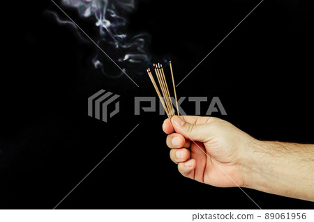 Hand and smoldering incense sticks with aroma smoke 89061956