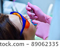 Woman patient with protective glasses and retractor for teeth whitening procedure 89062335