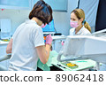 Woman dentist with assistant prepares patient for teeth whitening procedure. 89062418