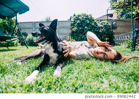 a young girl in the summer plays on the lawn with a dog, she scratches it while she licks and enjoys. Prores422. a young girl in the summer plays on the lawn with a dog, she scratches it while she licks and enjoys. Prores422. 89062442