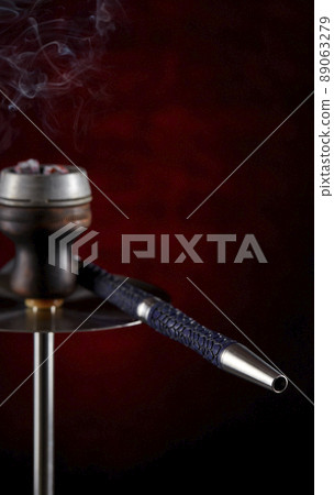 Fragment of a modern hookah on a beautiful dark background. Vertical location. Space for copying. Smoking a hookah. 89063279