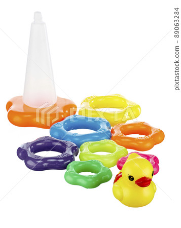 Pyramid toy with multi colored rings and a top in the form of a duck in disassembled form, isolated on a white background by a shadow. 89063284