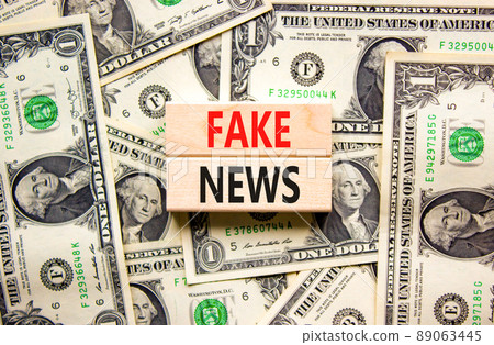 Fake news symbol. Wooden blocks with concept words Fake news on beautiful background from dollar bills. Business media and fake news concept. Copy space. Fake news symbol. Wooden blocks with concept words Fake news on beautiful background from dollar bills. Business media and fake news concept. Copy space. 89063445