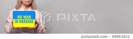 No war in Ukraine concept. Female hands holding tablet with colors of Ukrainian flag 89063822