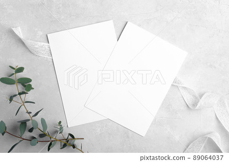 Two wedding stationery invitation cards mockup 5x7 on neutral grey marble background with eucalyptus leaves 89064037