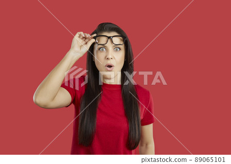 Young woman looking at something with surprised, shocked, astonished face expression 89065101