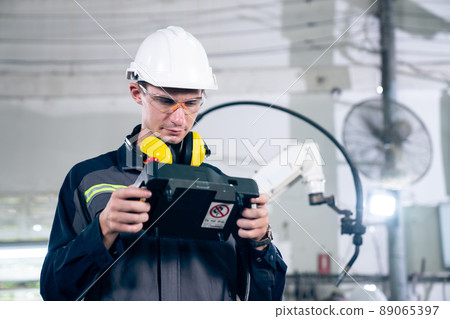 Young factory worker working with adept robotic arm Young factory worker working with adept robotic arm 89065397