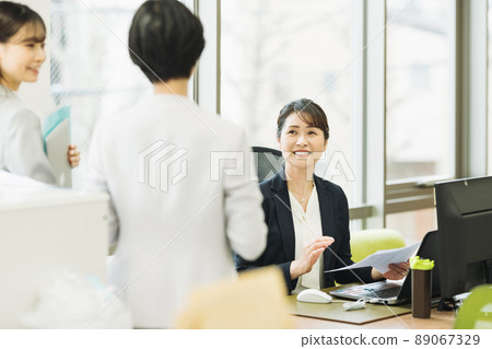 Middle career woman talking to subordinates in the office 89067329