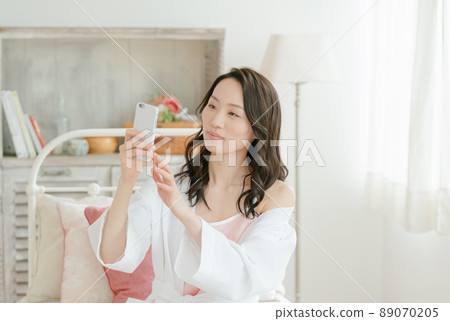 Young woman laughing at her smartphone Young woman laughing at her smartphone 89070205
