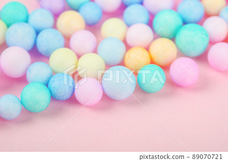 Foam beads of various colors brightly colored on pink pastel background with empty space. 89070721