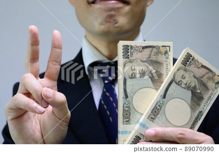A businessman holding a wad of bills and posing 89070990