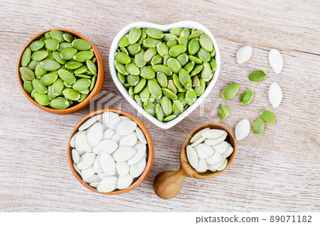 Pumpkin seeds green and unpeeled in wooden bowl. 89071182