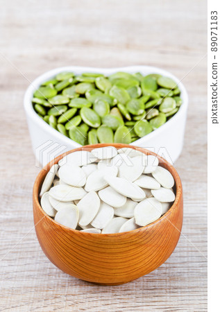 Pumpkin seeds green and unpeeled in wooden bowl. 89071183