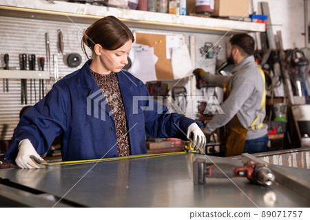 Workwoman measuring metal parts in workshop Workwoman measuring metal parts in workshop 89071757