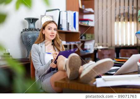 Office worker sitting at desk with legs on table Office worker sitting at desk with legs on table 89071763