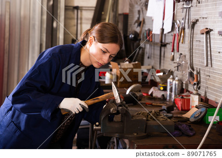 Young woman mechanic working with hand hammer 89071765
