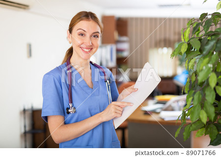 Nurse standing in hall with clipboard in hands Nurse standing in hall with clipboard in hands 89071766