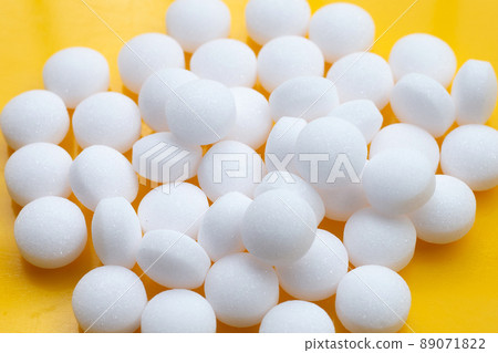 Naphthalene mothballs on yellow background. 89071822
