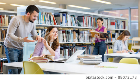 Woman showing stop gesture to annoying man in library 89072178