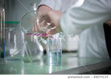 Table full of flasks. Chemical lab. Hands pouring liquid Table full of flasks. Chemical lab. Hands pouring liquid 89074135