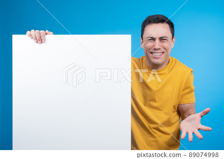 Confused smiling man demonstrating blank banner for advert Confused smiling man demonstrating blank banner for advert 89074998