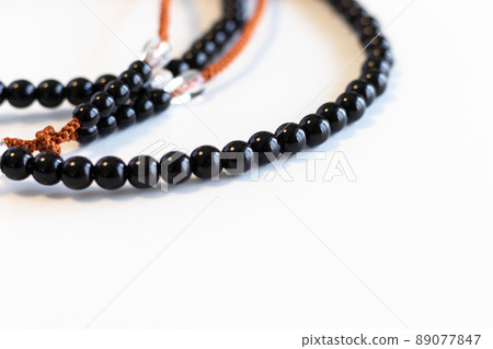 Black beads on a white table Black beads on a white table 89077847