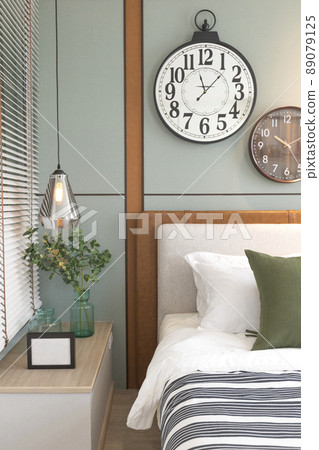 Bright bedroom interior with large green bed, hanging lamp and oak wooden floor. 89079125