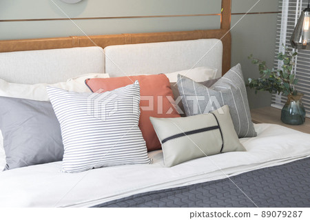 Stylish interior of modern bedroom. White and pastel orange design pillow in cozy bedroom. Stylish interior of modern bedroom. White and pastel orange design pillow in cozy bedroom. 89079287