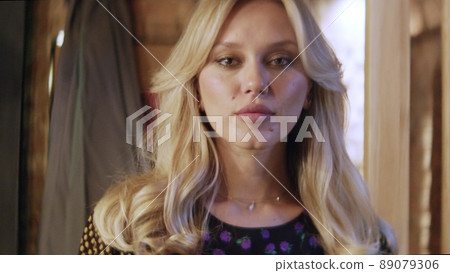 Portrait of a beautiful young blonde woman looking into the camera and smiling charmingly. The girl in the bar. 89079306