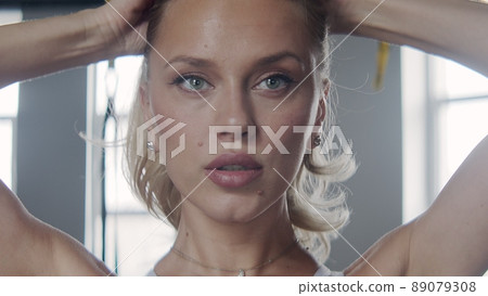 Close-up of a young woman putting her hair in a ponytail before going in for sports. Gym Close-up of a young woman putting her hair in a ponytail before going in for sports. Gym 89079308