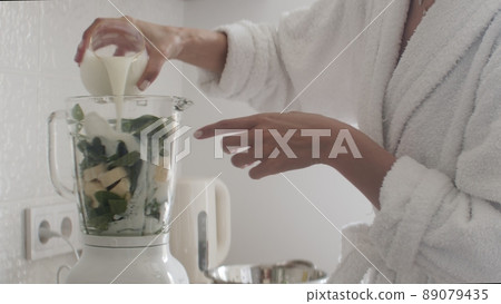 Close-up. Women's hands put ingredients in a blender. The girl is preparing a smoothie. Close-up. Women's hands put ingredients in a blender. The girl is preparing a smoothie. 89079435