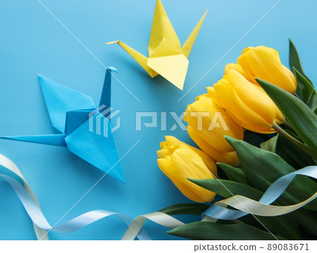 Yellow tulips and origami paper birds on a blue background Yellow tulips and origami paper birds on a blue background 89083671
