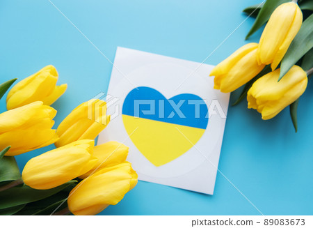 Card with a heart in the colors of the Ukrainian flag and yellow tulips on a blue background Card with a heart in the colors of the Ukrainian flag and yellow tulips on a blue background 89083673