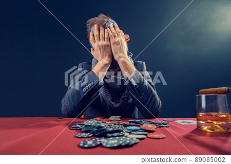 A wealthy mature man drinking brandy and playing poker with the excitement in a casino.  89085002