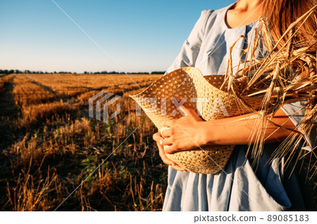 Ukrainian woman in blue linen dress with wheat spikelets on wheat fields. War in Ukraine threatens global wheat supply 89085183
