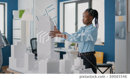 Woman placing blueprints plan on table to design building model and construction layout. Architect using maquette and industrial sketch to create structure for project development. Woman placing blueprints plan on table to design building model and construction layout. Architect using maquette and industrial sketch to create structure for project development. 89085546