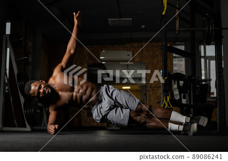 Shirtless african american man doing an elbow side plank in the gym. 89086241