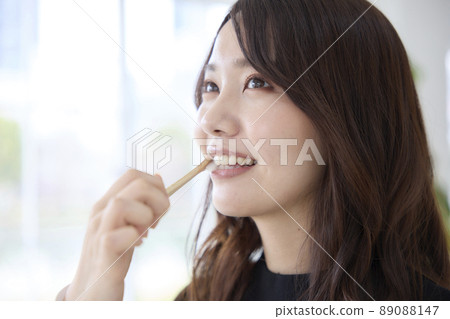 A woman brushing her teeth with a bamboo toothbrush 89088147