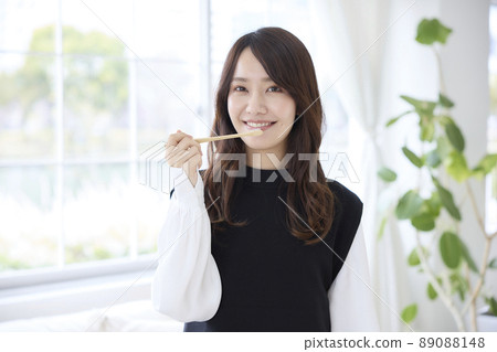 A woman brushing her teeth with a bamboo toothbrush A woman brushing her teeth with a bamboo toothbrush 89088148