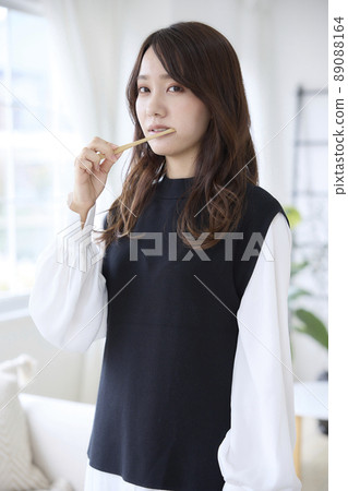 A woman brushing her teeth with a bamboo toothbrush 89088164