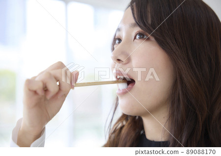 A woman brushing her teeth with a bamboo toothbrush A woman brushing her teeth with a bamboo toothbrush 89088170